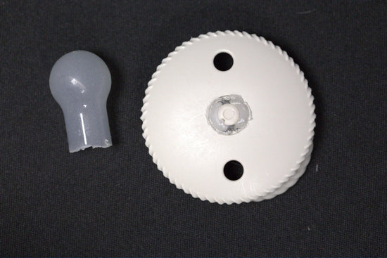 Detached silicone pacifier nipple with visible bite damage, placed next to the worn plastic shield - evidence of use by a teething child.